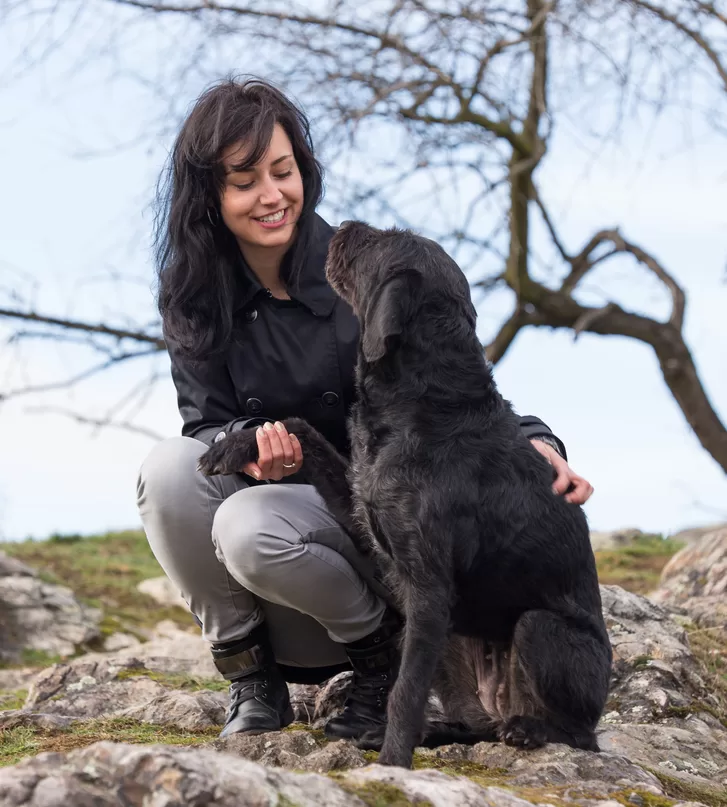 Beautiful girl with mutt black dog Amy on mountains, close-up.