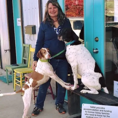Dog Trainer Lynne Fedorick standing with her two pointer dogs which are on a pedestal