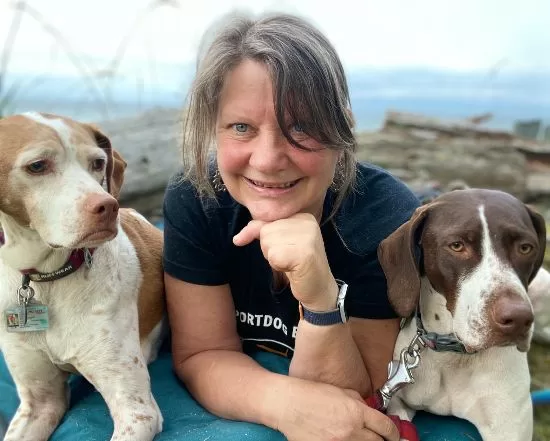 About page headshot of Lynne Fedorick and her two dogsfacing camera with 2 dogs